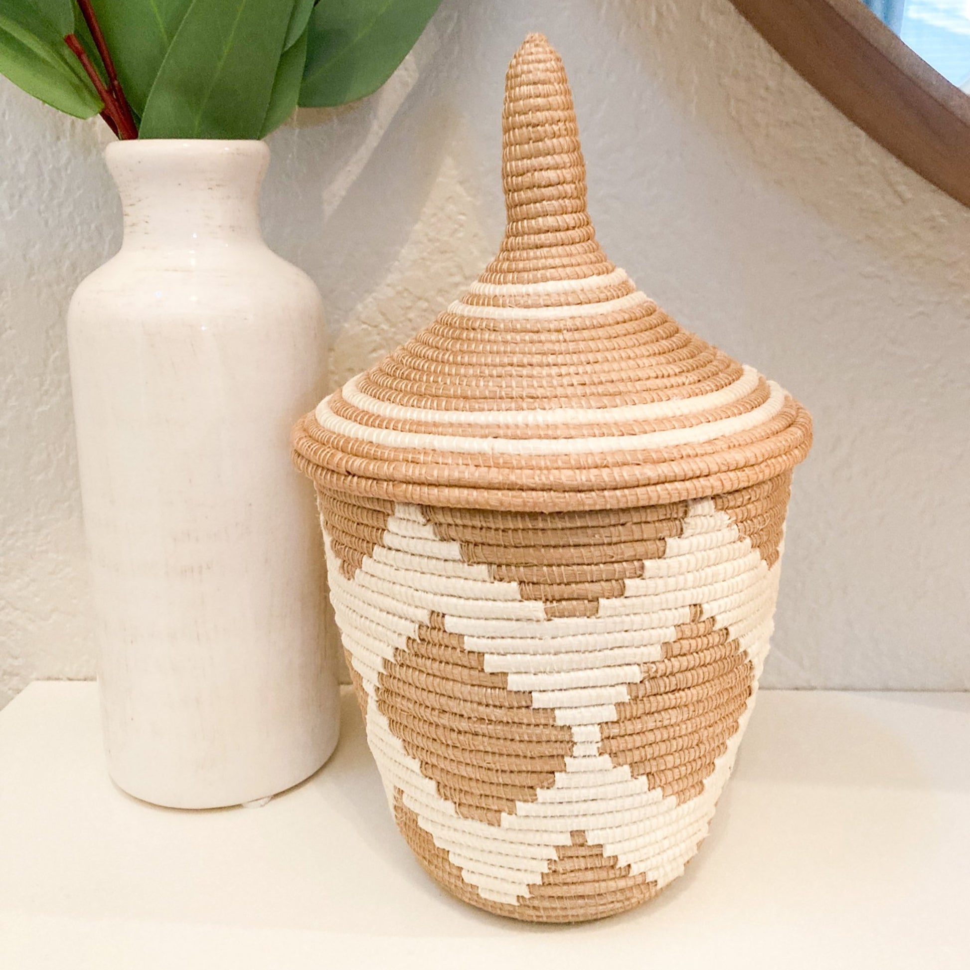 close up photo of a small woven basket with a white zig zag pattern and a pointed lid.