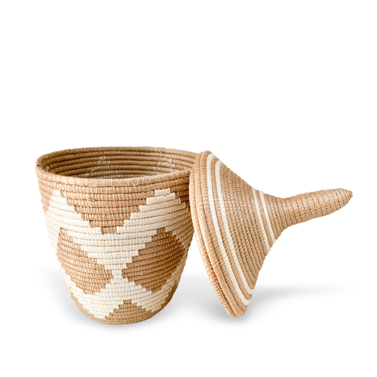 small woven basket with white zig zag pattern lid is laying against the basket